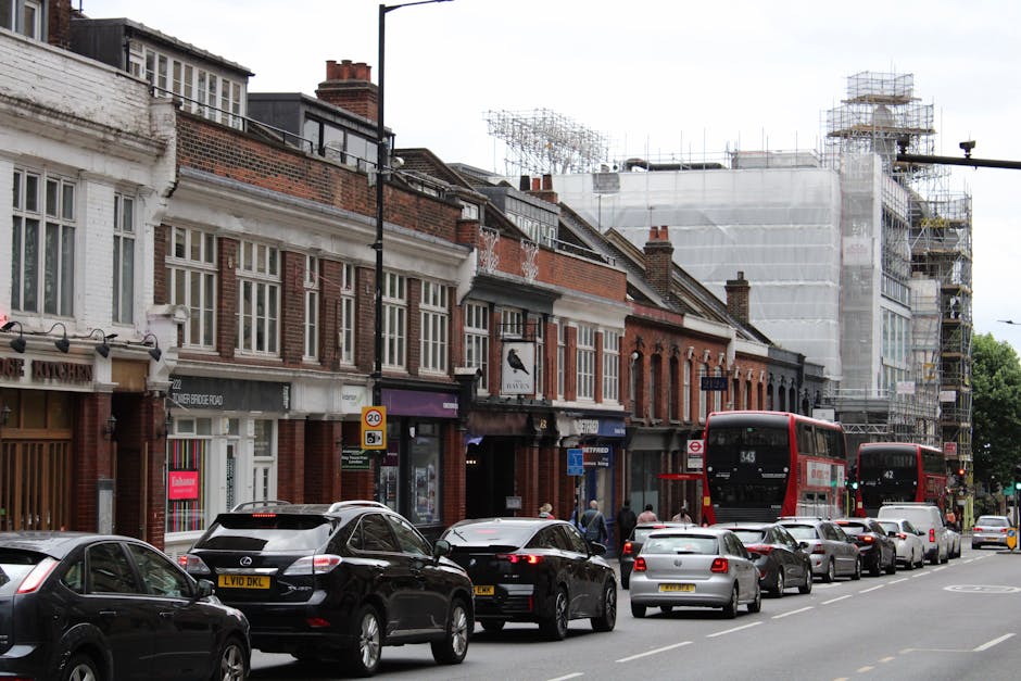 A street scene on Tooting High Street showing a row of multi-storey buildings with brick and cream facades, some featuring decorative architectural details. The pavement is visible on the left side of